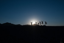 silhouettes of a group of people jumping up 