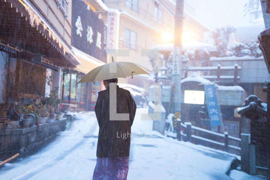a woman with an umbrella walking in snow 