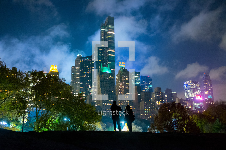 silhouette of a couple standing in front of city buildings 