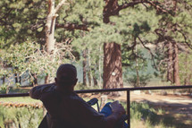 a man sitting in a chair on a back porch looking out at a lake 