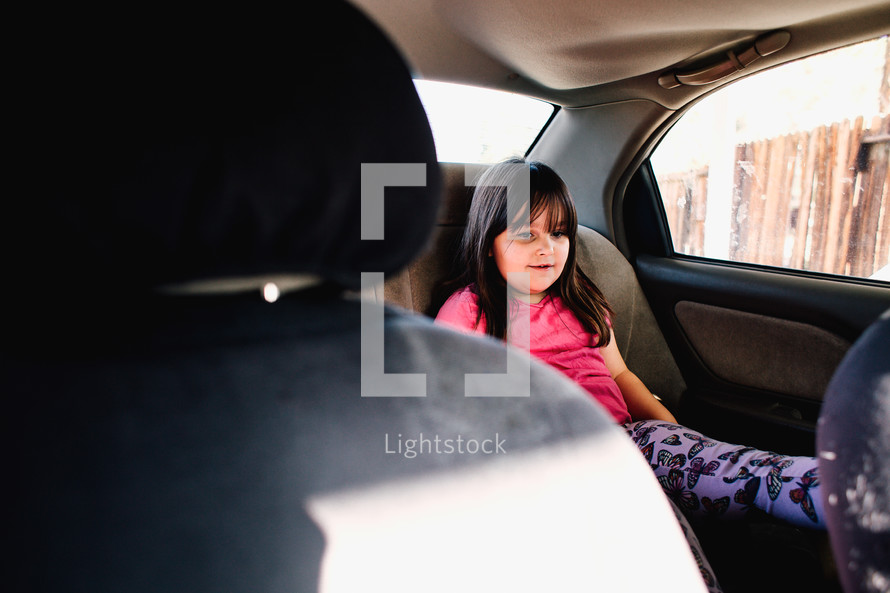 a child in a booster seat in the backseat of a car 
