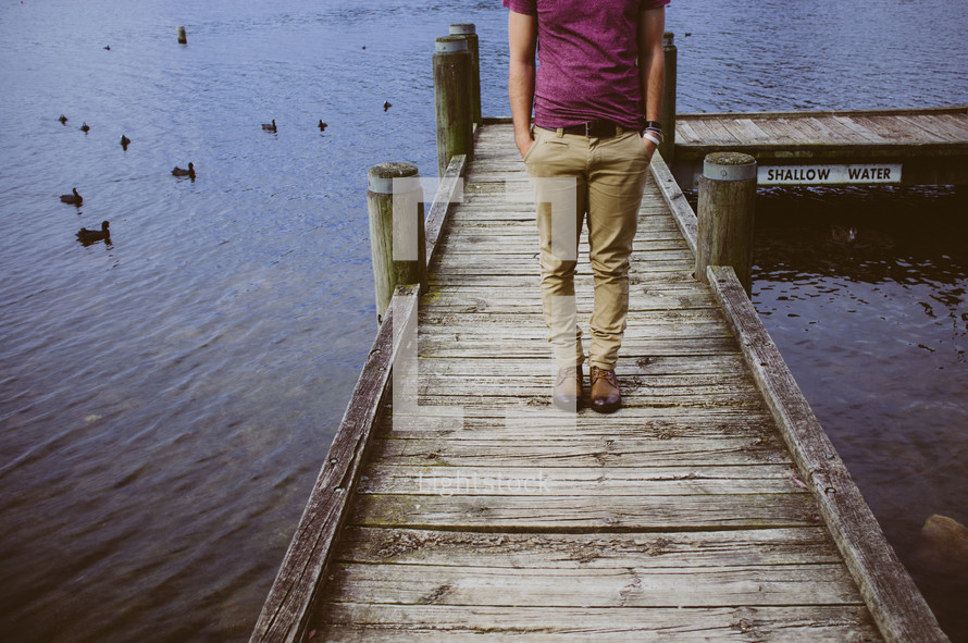 legs of a man standing on a dock 