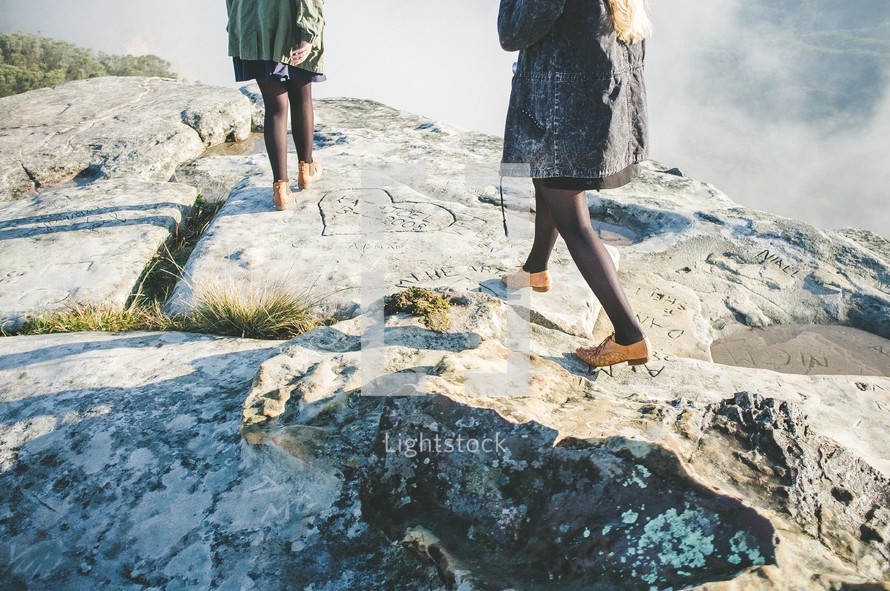 feet of women walking up a steep rock cliff