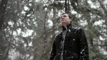 a man walking in a forest in falling snow 