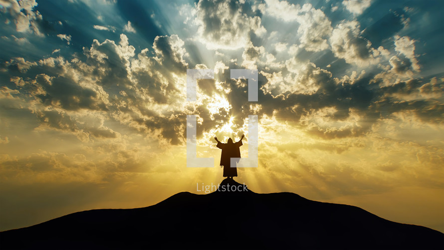 Silhouette of Jesus praying on a hill with mystic clouds behind Him.
