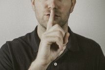man holding his finger over his mouth 