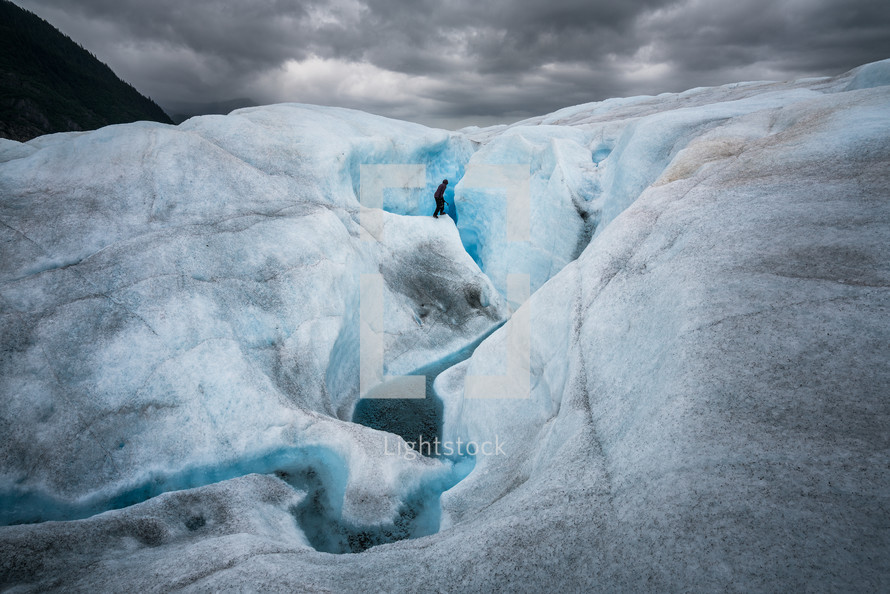 a woman hiking up a glacier 