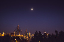 A tall bridge and city lights at night.