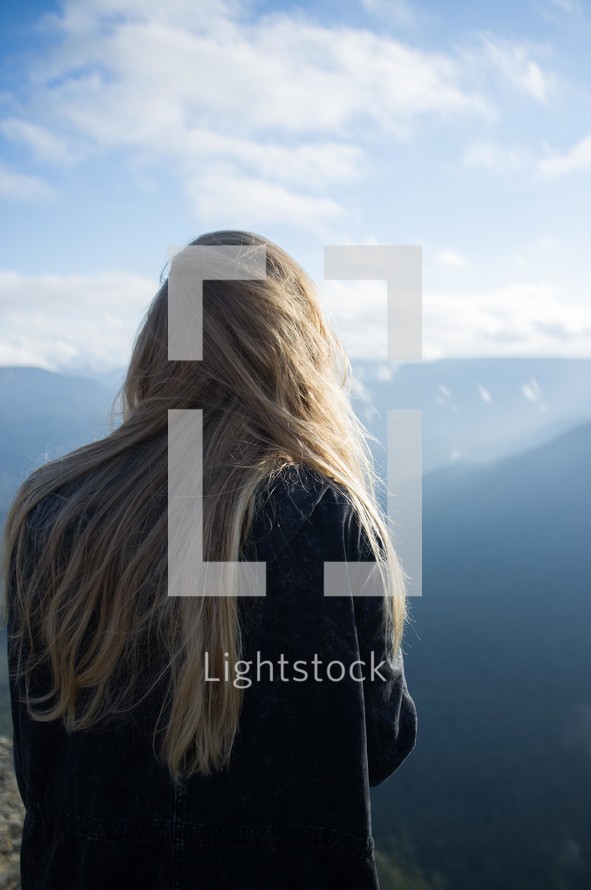 woman with long hair looking out at the mountains 