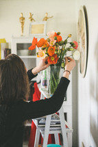 a woman arranging flowers in a vase 