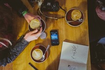 phone and camera on a table as they drink coffee 