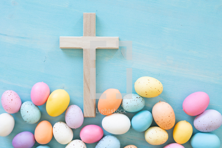 Wood cross with border of easter eggs on a blue background