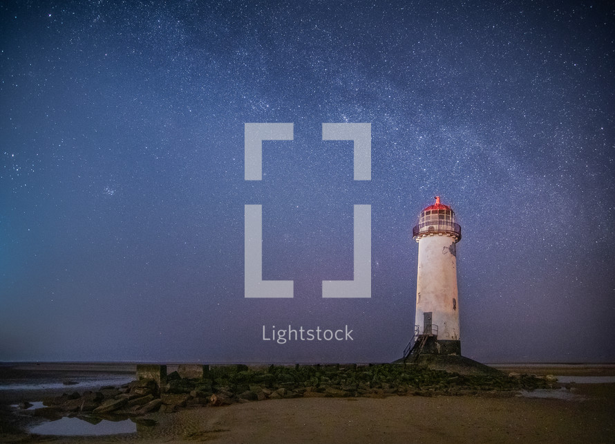Lighthouse under stars in the night sky 