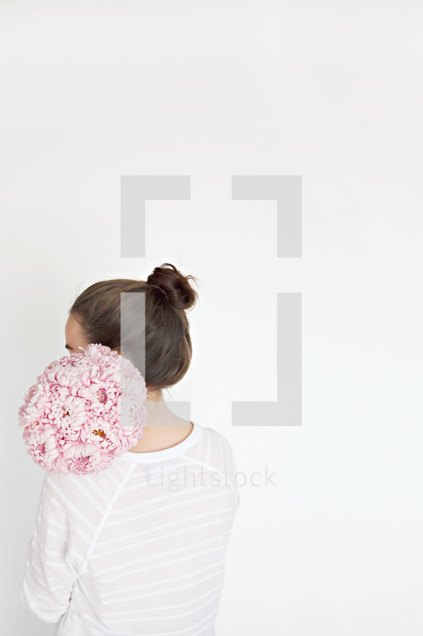 a woman holding a bouquet of pink flowers over her back 