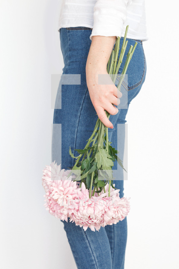 a woman holding a bouquet of flowers at her side 