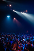 people sitting in rows in an auditorium and spotlights 
