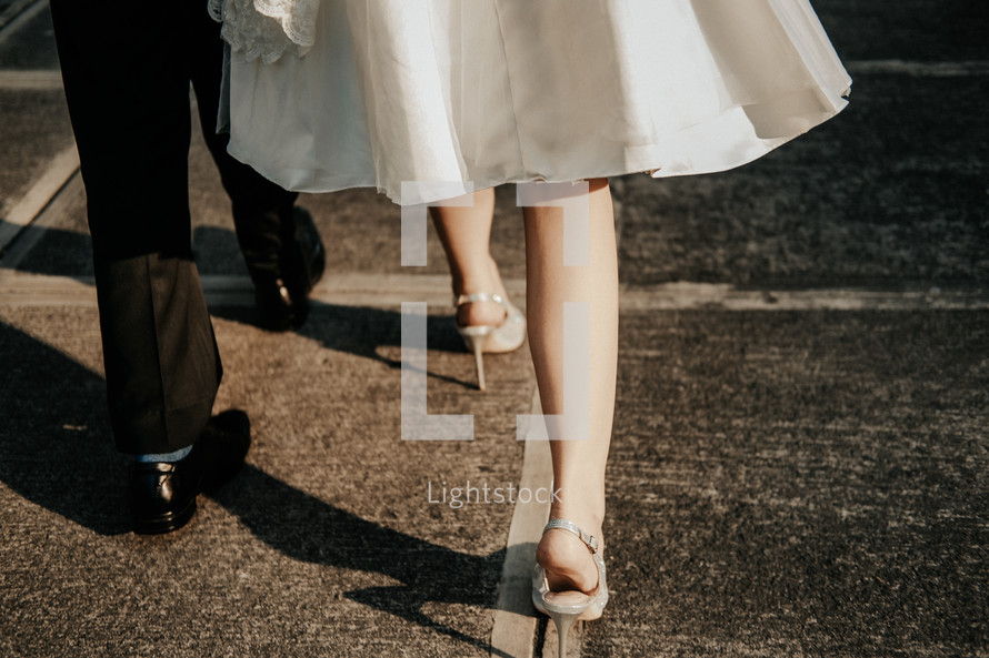 legs of a bride and groom on a crosswalk 