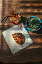 croissant and ice tea on a plate and succulent plant on a wood table 