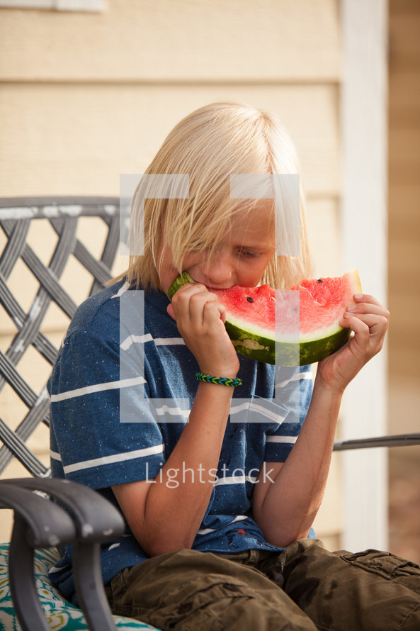 boy child eating a watermelon on a summer day
