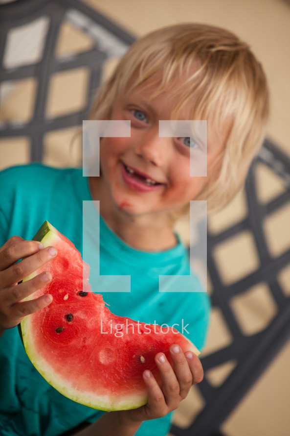 boy child eating a watermelon on a summer day 