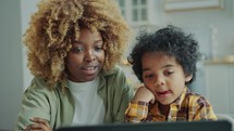 Curious Little Kid Watching Video on Laptop with Mom at Home
