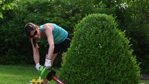 a woman trimming a hedge 