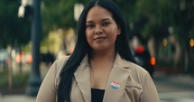 Young woman smiling with an ‘I Voted’ stickers and pin 