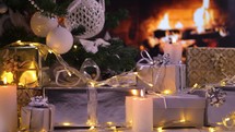 Gifts under the Christmas tree in front of fireplace with lights and burning candles. Christmas giving concept. 