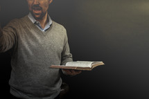 A man standing and preaching while holding a Bible.