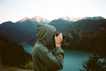 man in a hoodie taking a picture with a camera 