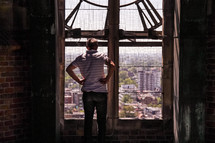 a man looking out a window in a clock tower at the city below 