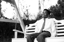 African American boy sitting on a swing 