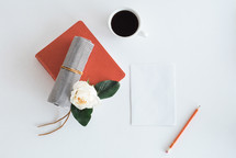 journal, paper, pencil, and coffee mug on a desk 