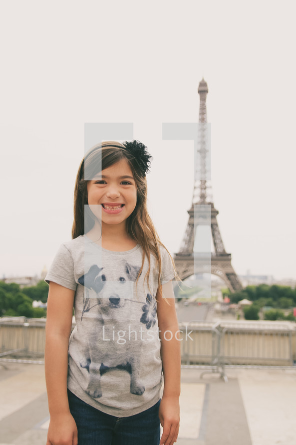 a little girl standing in front of the Eiffel Tower 