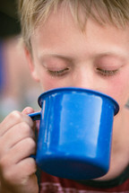 a boy drinking from a mug 