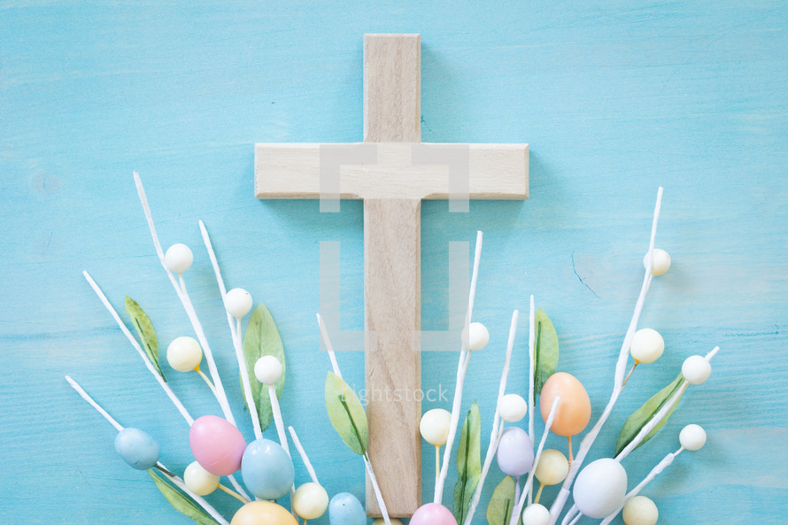 Cross with sprigs of easter eggs on a blue wood background