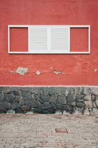 white shutters on a window on a red wall 