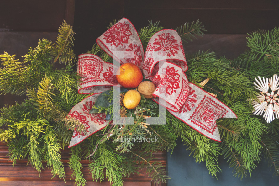 Christmas decorations stock photo featuring a mantle with pine garland wreath, chestnuts, ribbon and bow suitable for a social media post idea or presentation slide background. 
