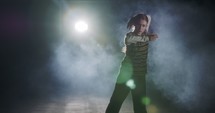 Young female dancer performing hip hop dance with strobe light and smoke background