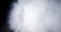 silhouette of a female dancer performing hip hop dance in slow motion with light and smoke background