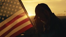 Silhouette of American soldier praying for memorial day against the flag outdoor