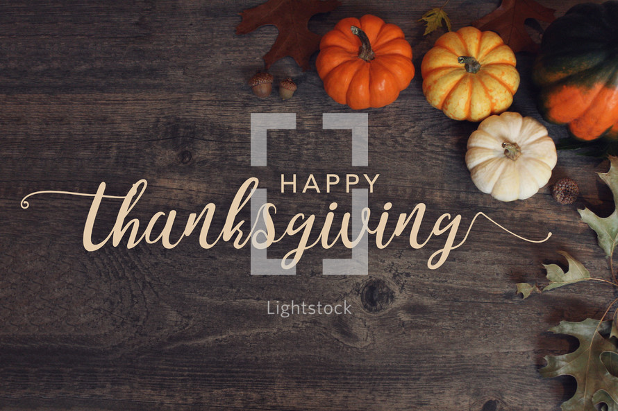 Happy Thanksgiving Typography Over Dark Wood Background with Pumpkins and Leaves