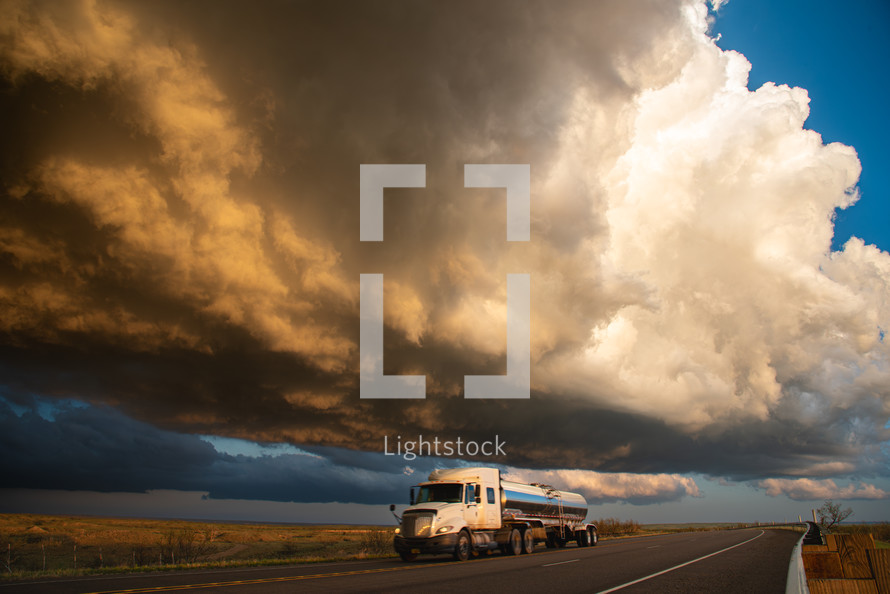 A Truck Passing Under Building Storm Clouds Full Of Sun Set Color