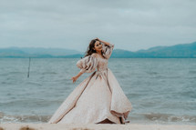 a woman in an elegant dress on a beach 