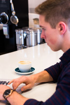 a man working on a laptop computer sitting in a coffee house 
