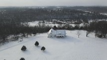 aerial view over a farmhouse in winter snow 