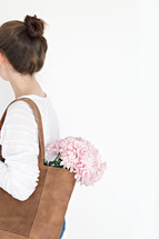 a woman carrying pink flowers in her purse 