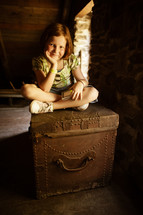 a child sitting on an old trunk 