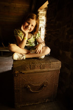 a girl sitting on an old trunk 