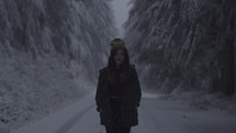 a woman standing on a snow covered dirt road 